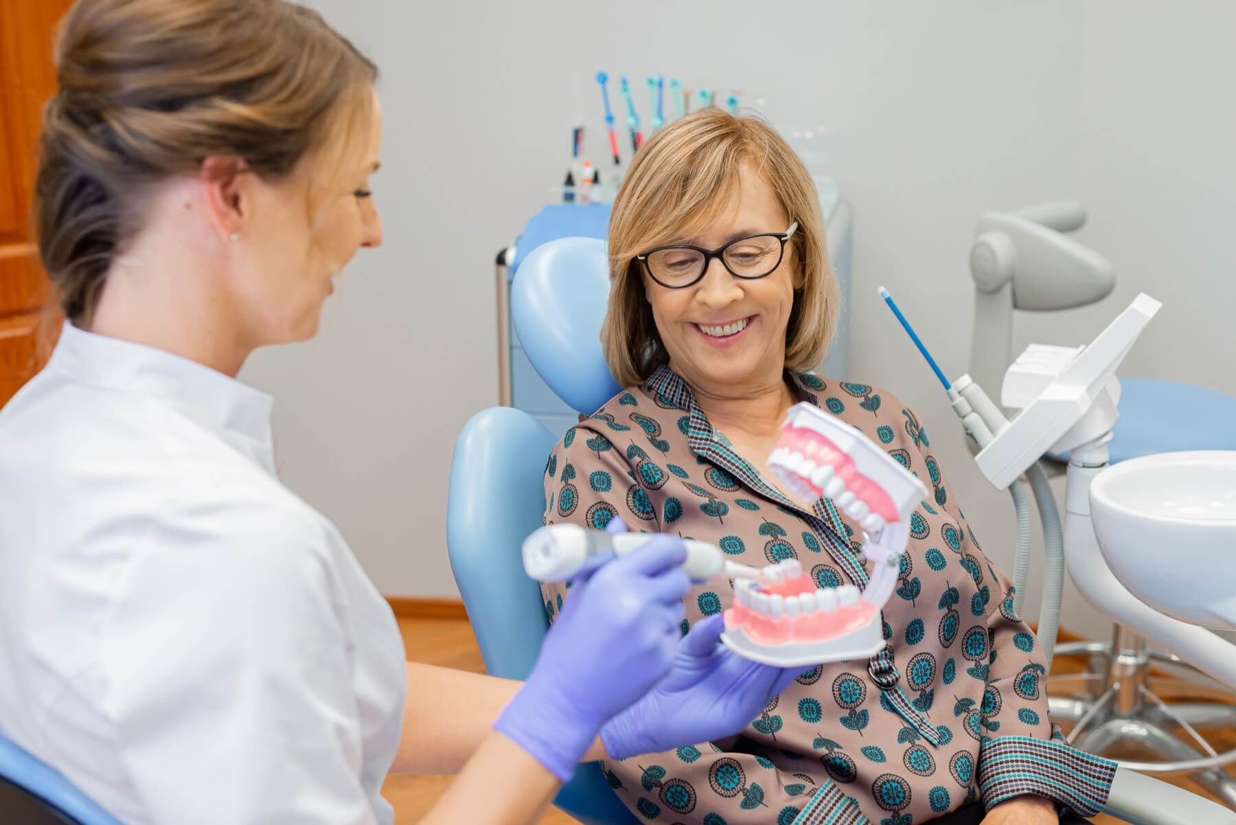 Dentystka wyjaśniająca proces leczenia stomatologicznego pacjentce